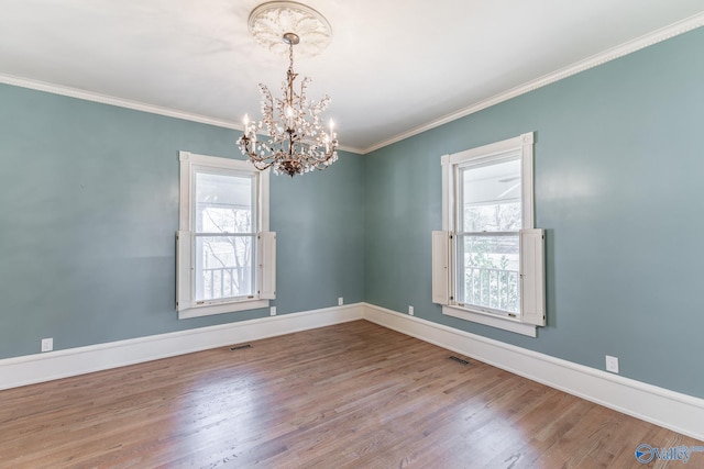 unfurnished room featuring a wealth of natural light, crown molding, baseboards, and wood finished floors