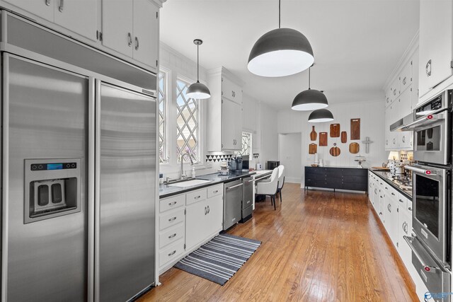 702 5th Ave SE, Cullman, AL 35055 - kitchen with light wood-type flooring, a warming drawer, appliances with stainless steel finishes, a sink, and dark countertops