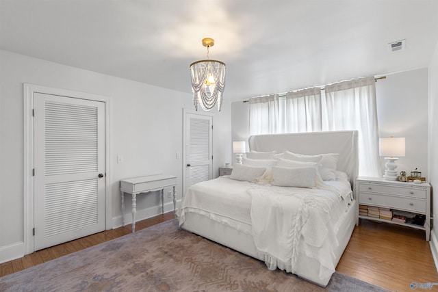 702 5th Ave SE, Cullman, AL 35055 - bedroom with two closets, visible vents, a chandelier, wood finished floors, and baseboards