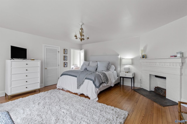 702 5th Ave SE, Cullman, AL 35055 - bedroom featuring a closet, baseboards, a fireplace with raised hearth, a chandelier, and wood finished floors