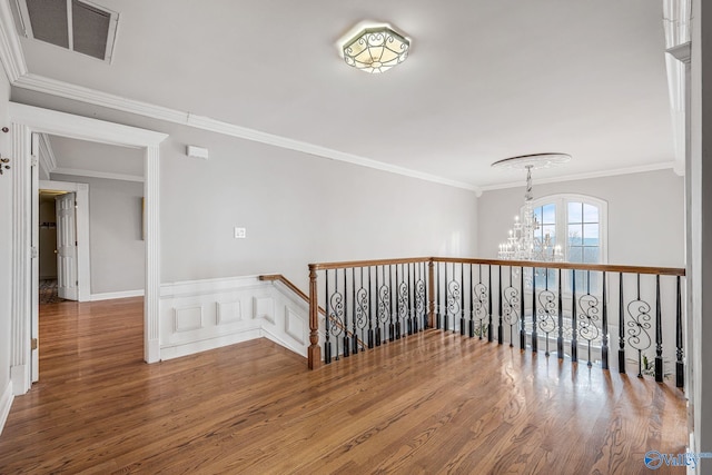 hallway featuring hardwood / wood-style flooring, crown molding, and a chandelier