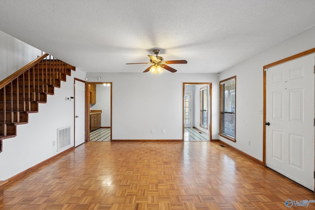 interior space with ceiling fan, light parquet flooring, and a textured ceiling