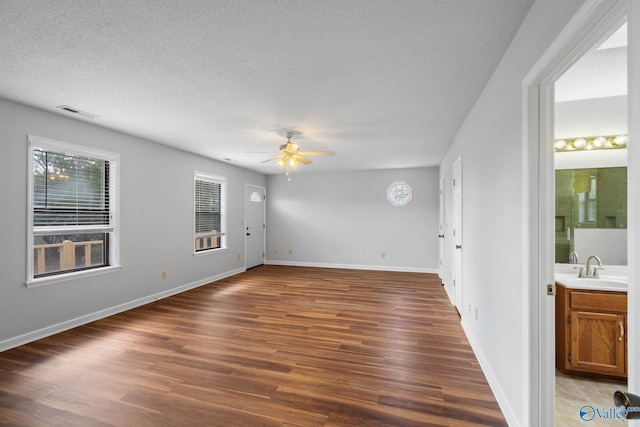 spare room featuring ceiling fan, dark wood-type flooring, sink, and a textured ceiling