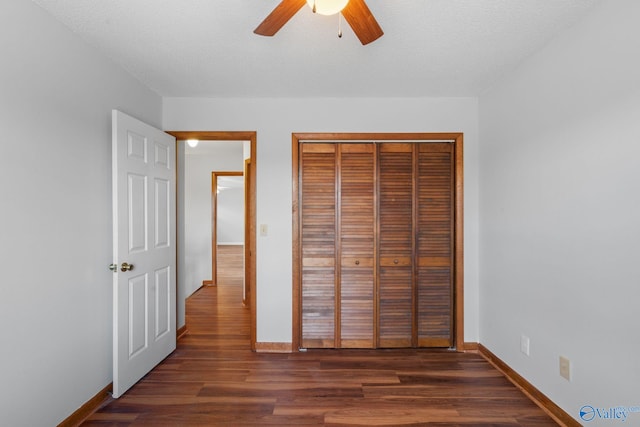 unfurnished bedroom with dark hardwood / wood-style flooring, ceiling fan, a closet, and a textured ceiling