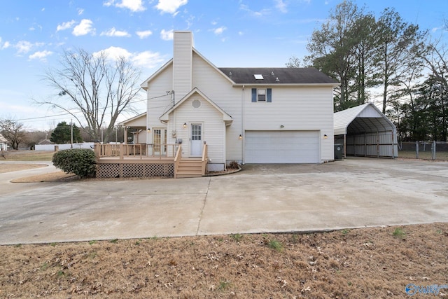 back of property with a carport, a wooden deck, and a garage