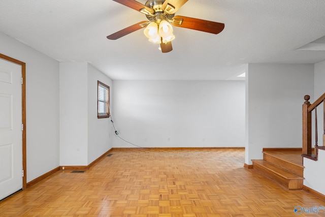 spare room with light parquet floors, ceiling fan, and a textured ceiling