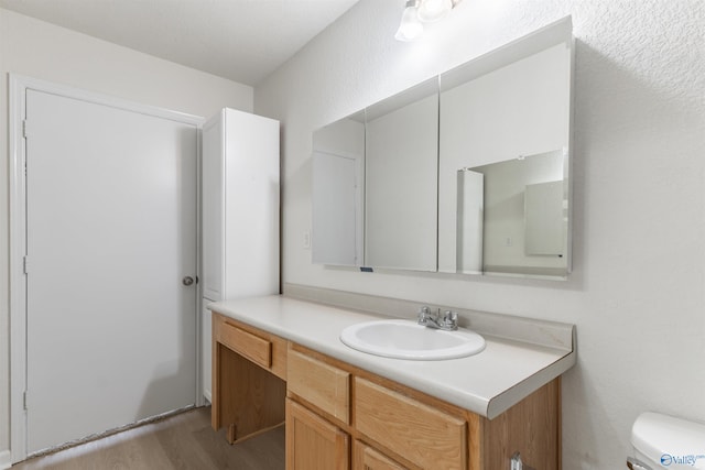 bathroom with vanity, toilet, and hardwood / wood-style flooring