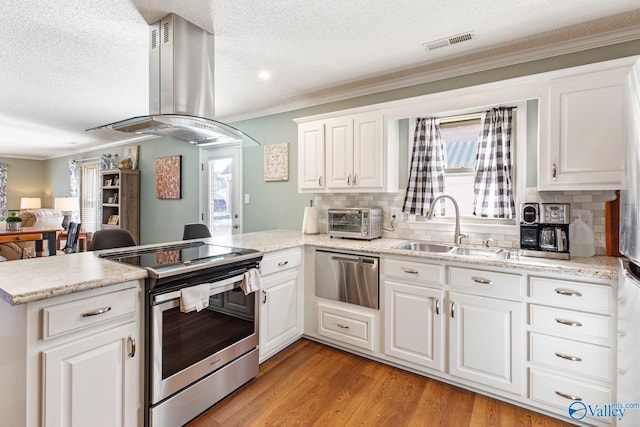 kitchen featuring stainless steel electric stove, visible vents, a sink, island range hood, and a peninsula