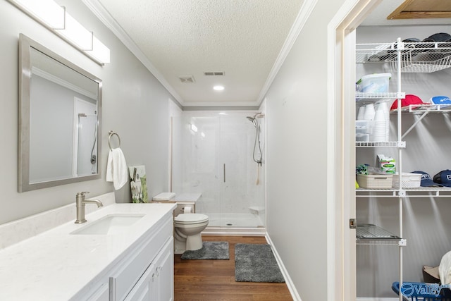 full bathroom with a textured ceiling, a shower stall, toilet, and crown molding