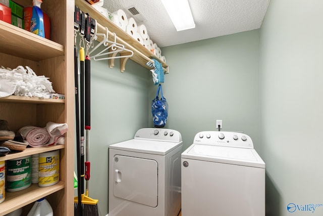 washroom featuring a textured ceiling, laundry area, and washing machine and clothes dryer