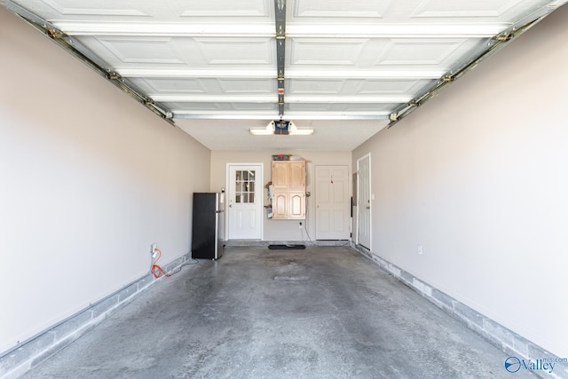 garage with a garage door opener, freestanding refrigerator, and baseboards