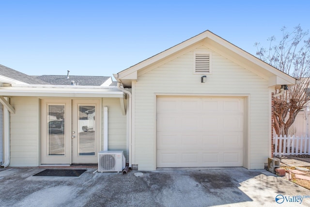 garage featuring ac unit, fence, and concrete driveway