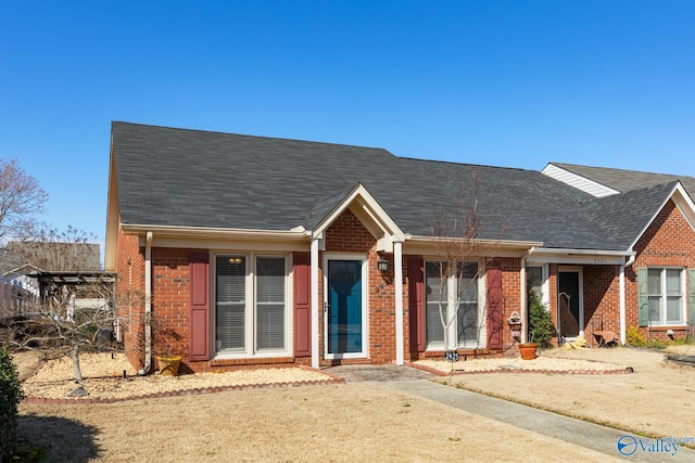 single story home featuring roof with shingles and brick siding