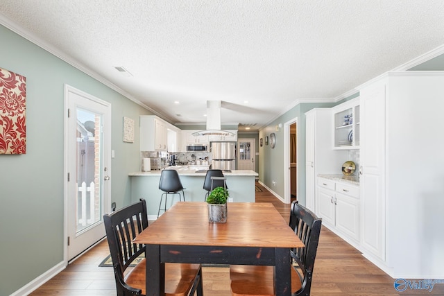 dining area with a textured ceiling, ornamental molding, wood finished floors, and a wealth of natural light