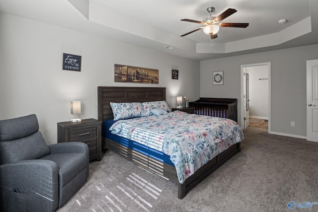 carpeted bedroom featuring a tray ceiling and ceiling fan