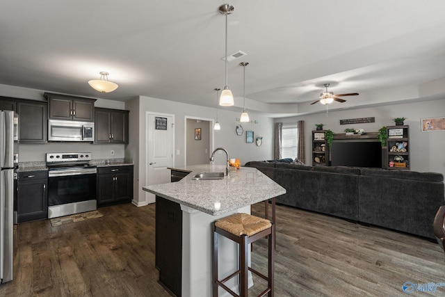 kitchen featuring appliances with stainless steel finishes, a kitchen bar, ceiling fan, dark hardwood / wood-style floors, and sink