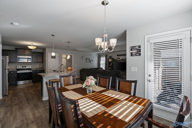 dining space featuring sink, dark wood-type flooring, and a notable chandelier