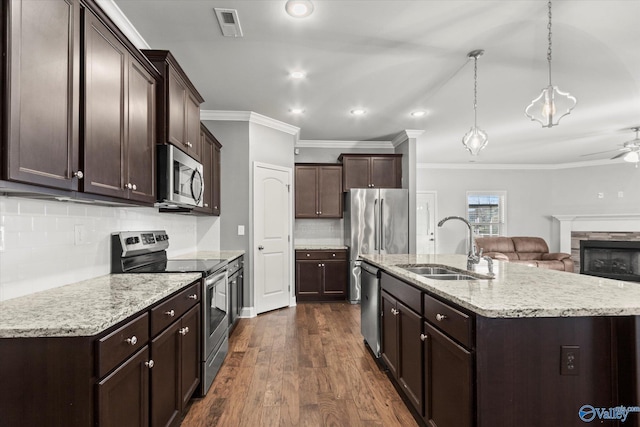 kitchen with sink, tasteful backsplash, appliances with stainless steel finishes, an island with sink, and pendant lighting