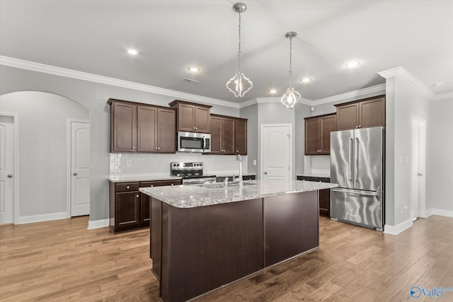 kitchen with decorative light fixtures, decorative backsplash, dark brown cabinetry, stainless steel appliances, and light stone countertops