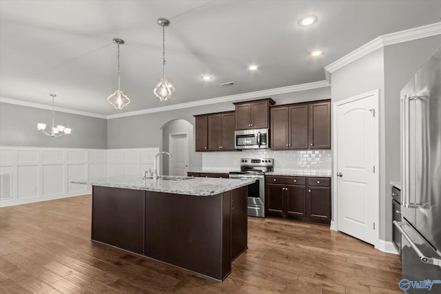 kitchen featuring sink, decorative light fixtures, dark brown cabinets, a center island with sink, and appliances with stainless steel finishes