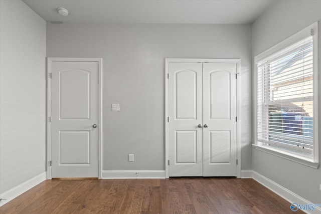 unfurnished bedroom with dark hardwood / wood-style floors and a closet