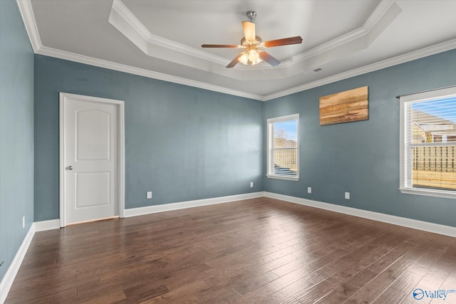 unfurnished room with ornamental molding, dark hardwood / wood-style flooring, and a tray ceiling