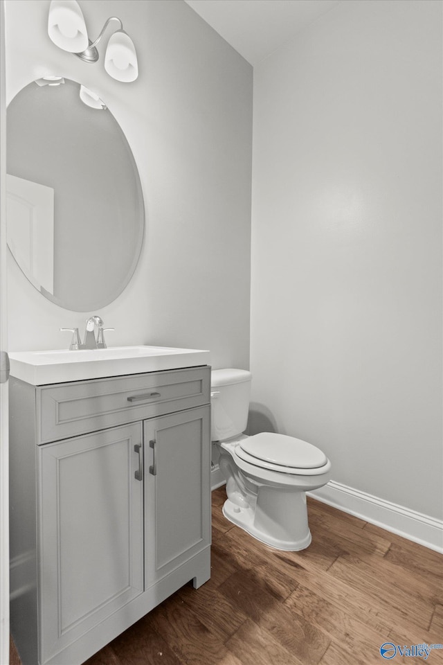 bathroom featuring wood-type flooring, toilet, and vanity