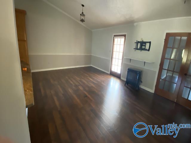 unfurnished living room with crown molding, lofted ceiling, dark wood-type flooring, and a fireplace