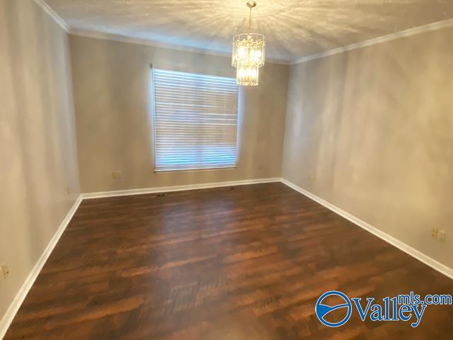 spare room with crown molding, dark hardwood / wood-style flooring, and a chandelier