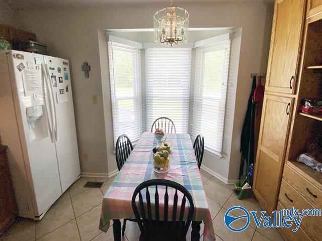 tiled dining room with a healthy amount of sunlight and an inviting chandelier