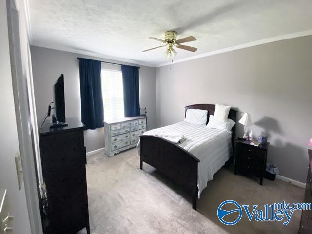 bedroom featuring light carpet, crown molding, and ceiling fan