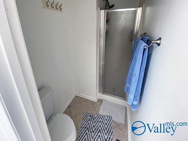 bathroom featuring tile patterned floors, toilet, and an enclosed shower