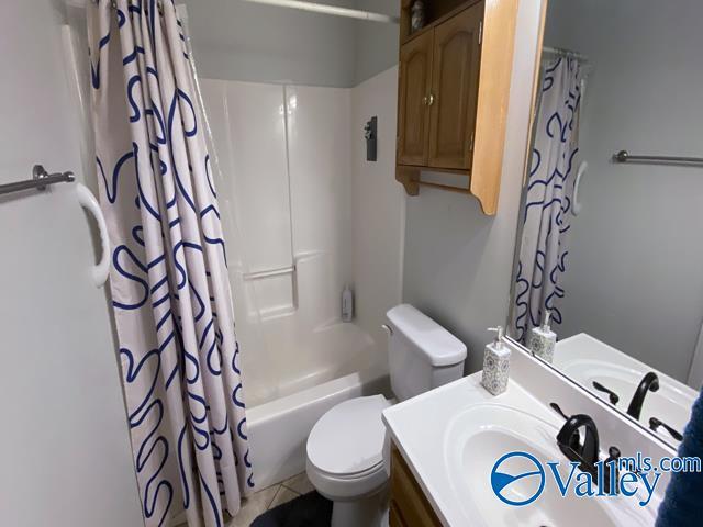 full bathroom featuring toilet, tile patterned floors, vanity, and shower / bathtub combination with curtain