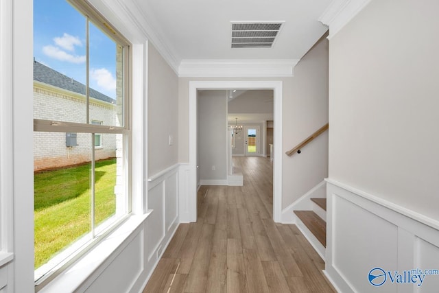 hallway featuring a notable chandelier, crown molding, a wealth of natural light, and light hardwood / wood-style floors