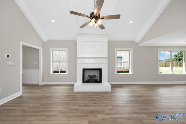 unfurnished living room with a brick fireplace, hardwood / wood-style flooring, high vaulted ceiling, and ceiling fan