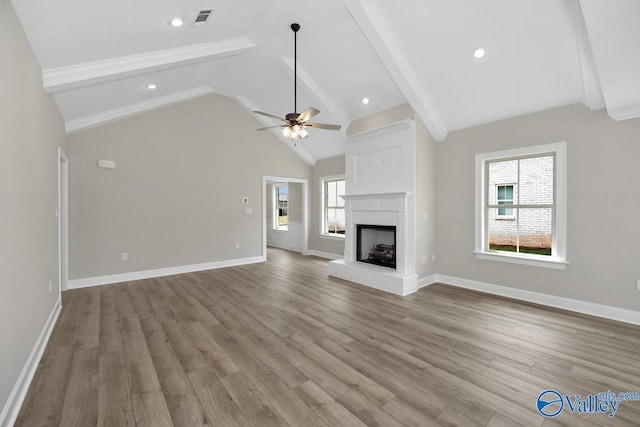 unfurnished living room featuring beamed ceiling, ceiling fan, light wood-type flooring, and a fireplace