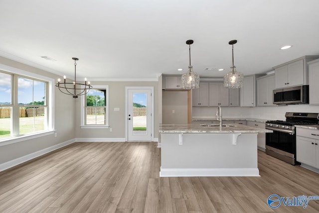 kitchen featuring sink, a breakfast bar area, gray cabinets, appliances with stainless steel finishes, and a kitchen island with sink