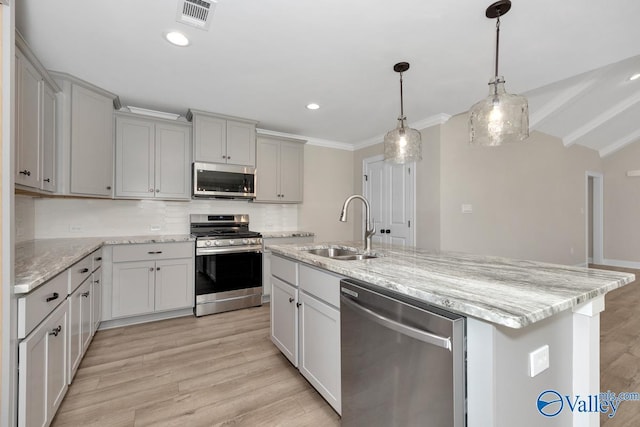 kitchen featuring sink, tasteful backsplash, light wood-type flooring, appliances with stainless steel finishes, and an island with sink