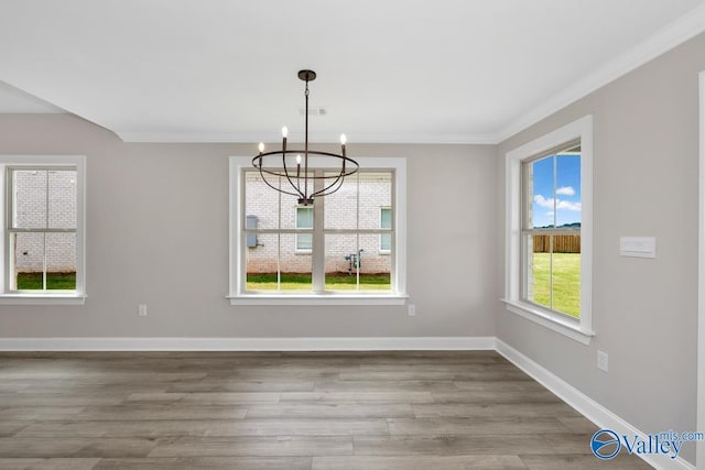 unfurnished dining area with hardwood / wood-style floors, ornamental molding, and a chandelier