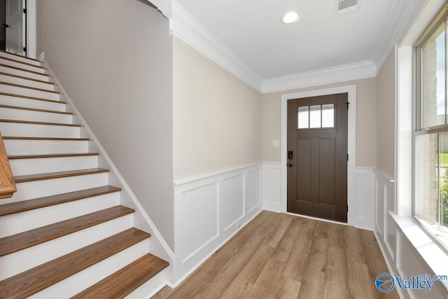 foyer with ornamental molding and light hardwood / wood-style floors