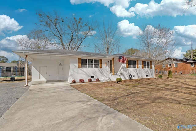 ranch-style house with a trampoline, an attached carport, and concrete driveway