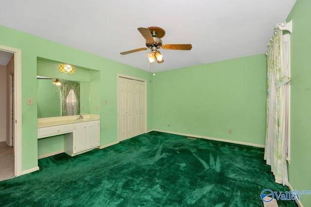 unfurnished bedroom featuring dark colored carpet, multiple windows, ceiling fan, and sink