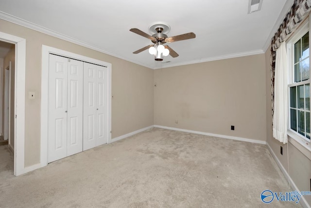 unfurnished bedroom with ceiling fan, light colored carpet, crown molding, and a closet