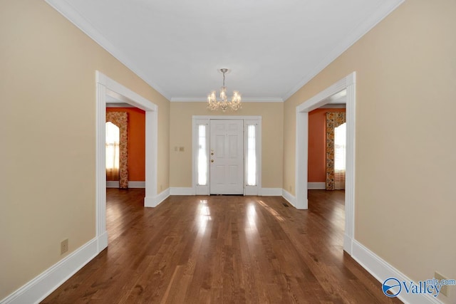 entryway with a chandelier, dark wood-type flooring, and ornamental molding