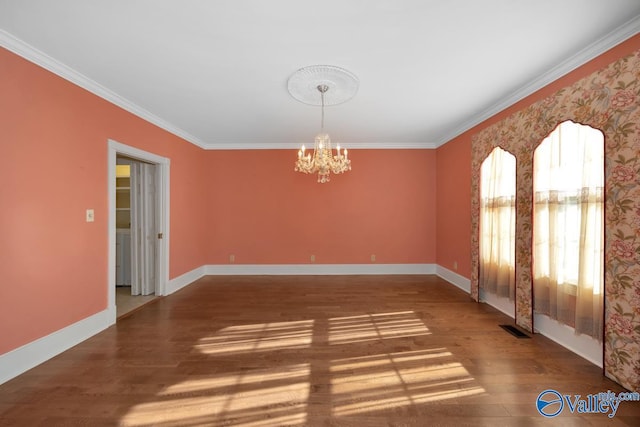 empty room featuring hardwood / wood-style floors, ornamental molding, and a notable chandelier