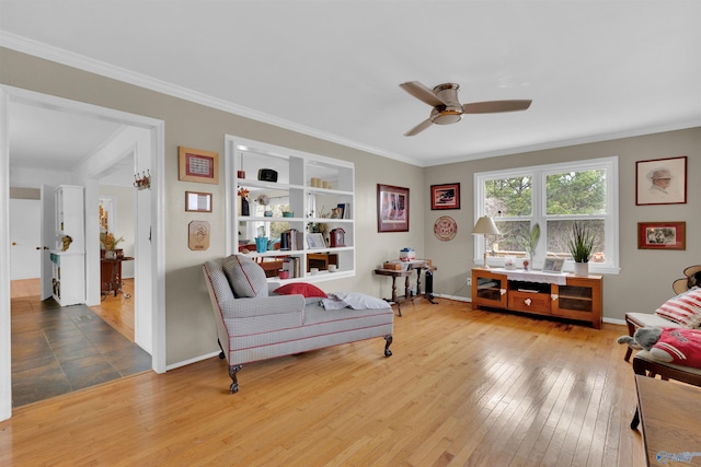 living area featuring hardwood / wood-style flooring, built in features, a ceiling fan, and ornamental molding