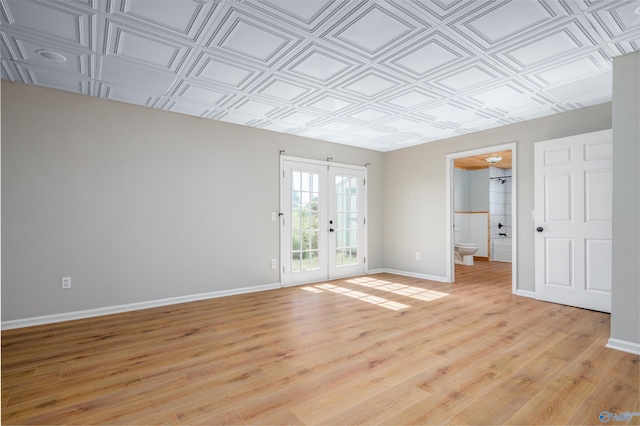 spare room featuring french doors and light hardwood / wood-style flooring