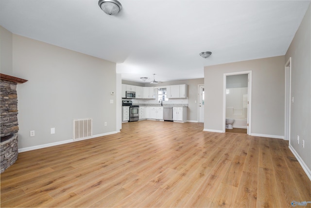 unfurnished living room featuring sink and light hardwood / wood-style floors