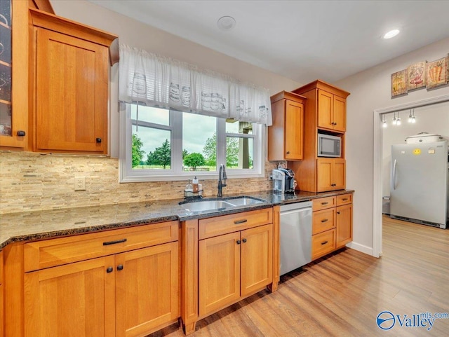 591 Nix Rd, Hazel Green, AL 35750 - kitchen with stainless steel appliances, a sink, dark stone counters, light wood-style floors, and brown cabinets