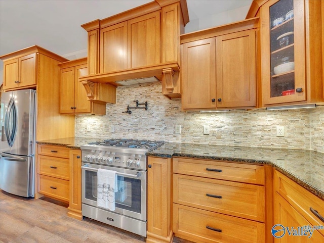 591 Nix Rd, Hazel Green, AL 35750 - kitchen with appliances with stainless steel finishes, dark stone counters, glass insert cabinets, light wood-type flooring, and backsplash